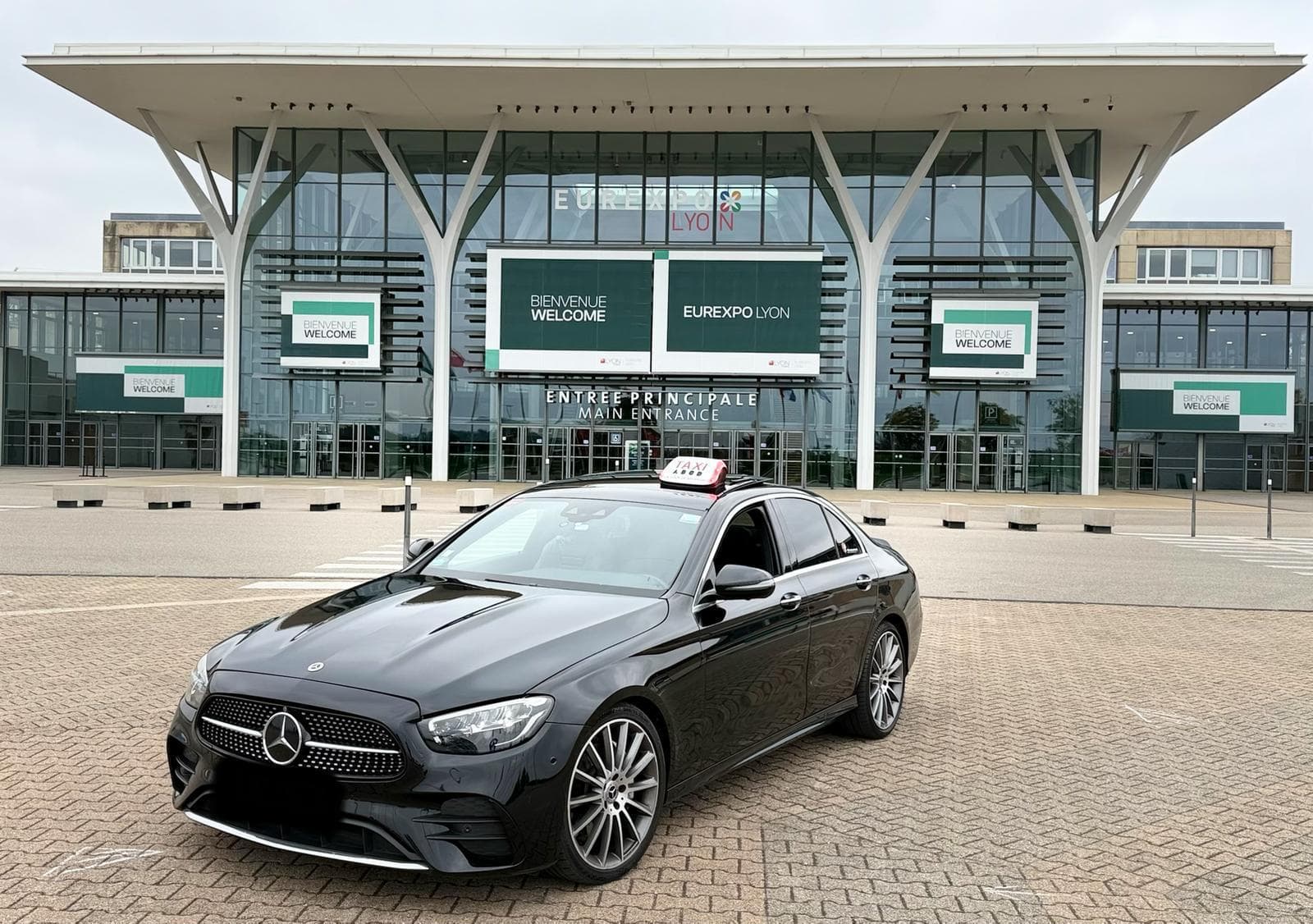 Berline Mercedes noire, taxi conventionné, garée devant Eurexpo Lyon
